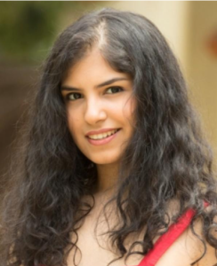 A student with long wavy brown hair and a red tank top